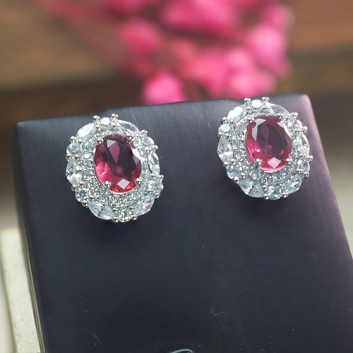 Ruby-red cubic zirconia halo earrings in a silver-tone setting, close-up