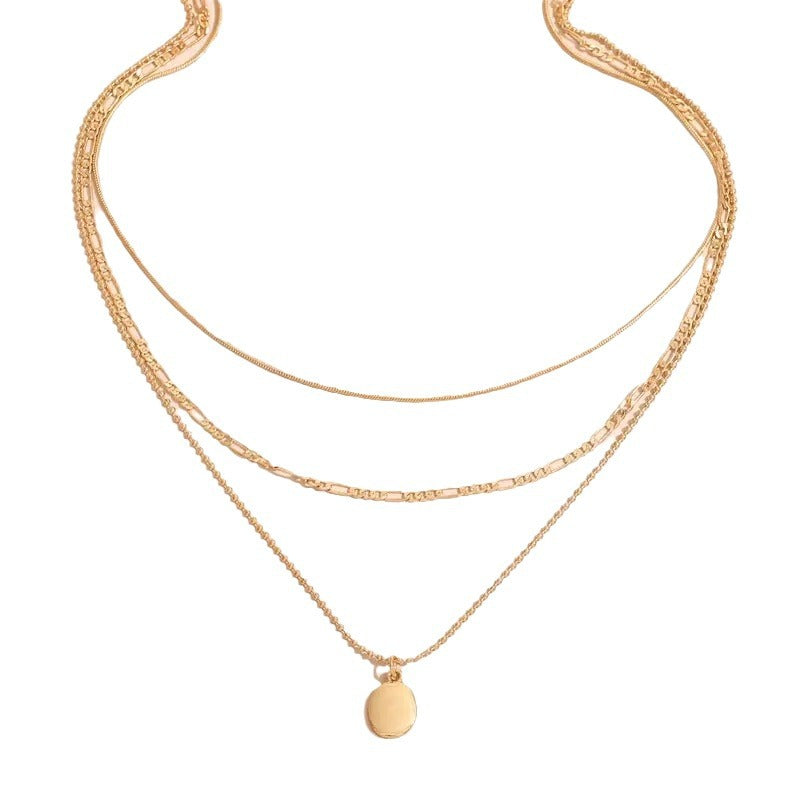 Triple-strand layered necklace with smooth oval pendant, close-up